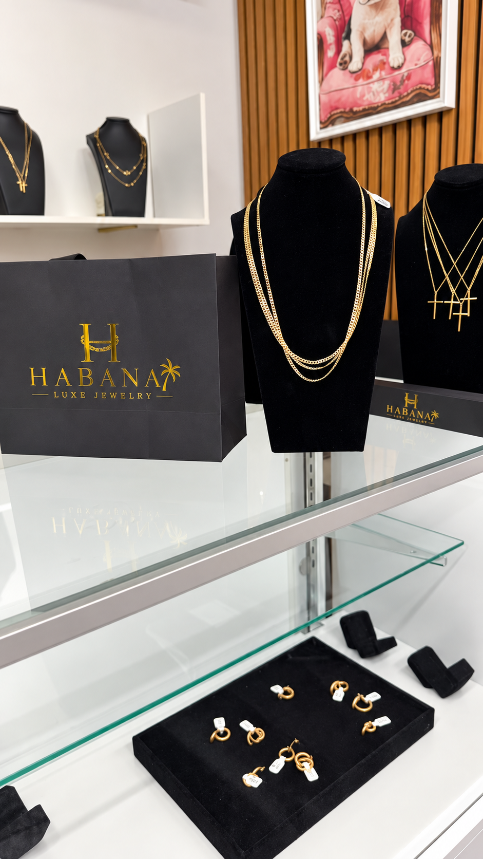 Vitrina de Habana Luxe Jewelry con collares de oro en exhibidores negros y bolsa de la marca
